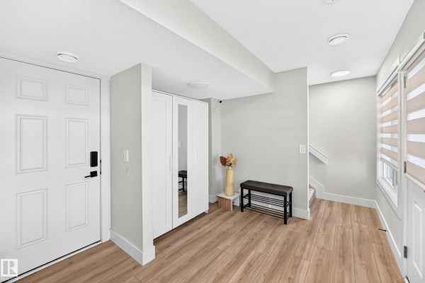 Townhouse entryway with white walls, wood-look flooring, a white closet, and a staircase to the right. - #70 16335 84 St Nw, Edmonton