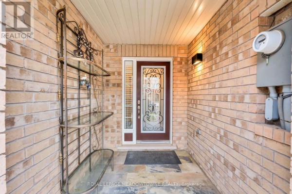 Front exterior view of a brick townhouse complex with attached garages and tidy front yards. - 70 Betterton Crescent, Brampton