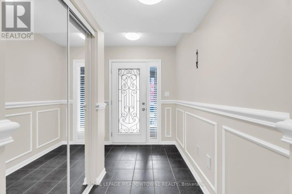View of a brick townhouse complex exterior with multiple garages and entrances on a street. - 70 Betterton Crescent, Brampton