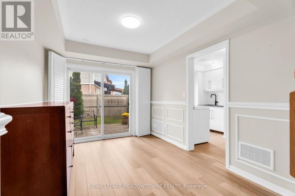 Covered front porch entrance of a townhouse with a glass-paneled door and decorative metal shelving. - 70 Betterton Crescent, Brampton