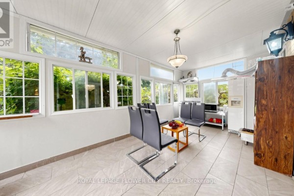 Sunroom with windows, pendant light, dining set, and appliances - 70 Boom Road Vaughan