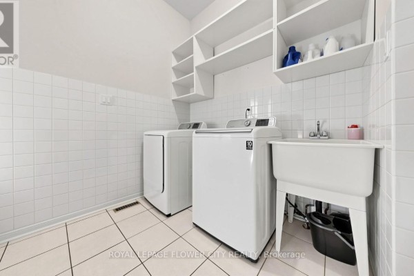 Washer, dryer, utility sink, and shelving in laundry room - 70 Boom Road Vaughan