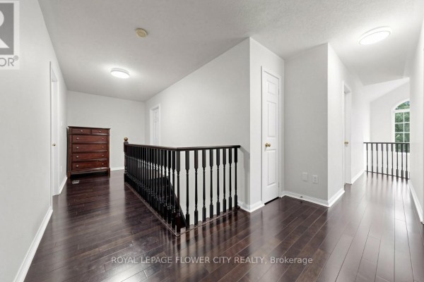 Hallway with dark hardwood floors, banister, and chest of drawers - 70 Boom Road Vaughan