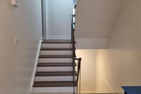 Interior staircase with dark wood treads and white risers, leading upwards. - 70 Copperwood Square, Toronto