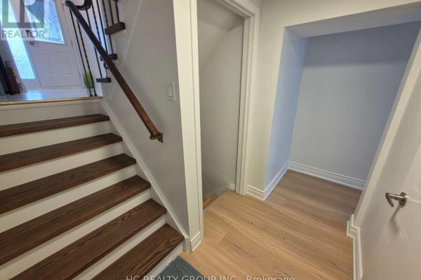 Staircase landing with wood flooring and adjacent hallway with a closet. - 70 Copperwood Square, Toronto