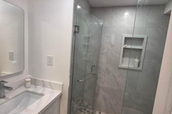 Modern bathroom with a vanity, marble countertop, and a glass-enclosed shower. - 70 Copperwood Square, Toronto