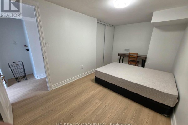 Bedroom with a bed, desk, chair, and a sliding door closet. - 70 Copperwood Square, Toronto