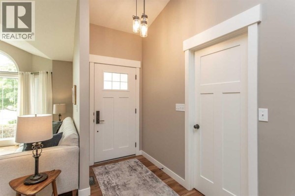 Interior view of a home's entryway with white doors, beige walls, and a patterned rug. - 70 Densmore Crescent, Red Deer