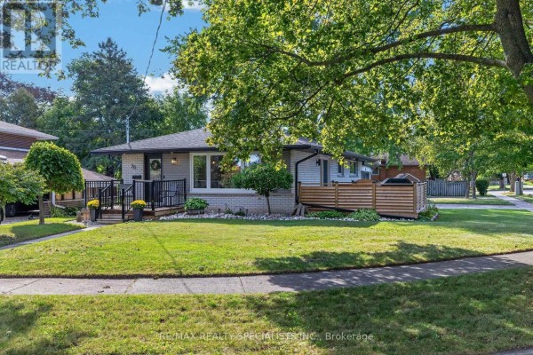 Side exterior view of the house showing a grass lawn and large trees. - 70 Duncairn Avenue, Kitchener