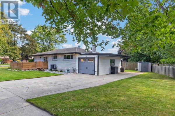 Rear exterior view of the house, garage, driveway, and a fenced backyard. - 70 Duncairn Avenue, Kitchener