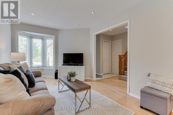 Living room with bay window, sofa, coffee table, and view of the foyer. - 70 Dunsmore Crescent, Richmond Hill