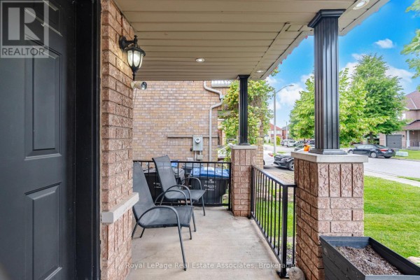 Close-up of a covered front porch with chairs, brick pillars, and a street view. - 70 Echoridge Drive, Brampton