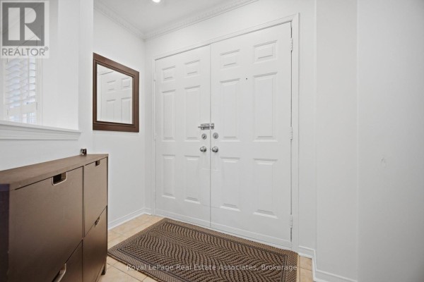 Interior entryway with a dark wood shoe cabinet, a mirror, and double white doors. - 70 Echoridge Drive, Brampton