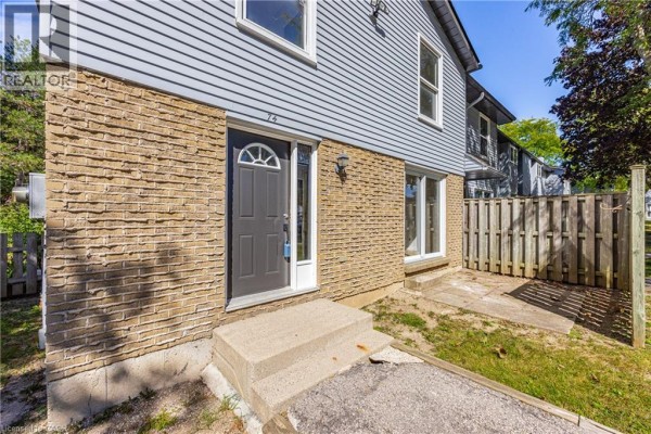 Close-up of the townhouse entrance with grey door, brick facade, and light blue siding. - 70 Fiddlers Green Road Unit# 74, London
