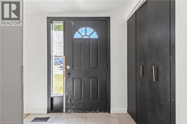 Interior view of the entrance hallway with a black door, transom window, and tall dark closet doors. - 70 Fiddlers Green Road Unit# 74, London