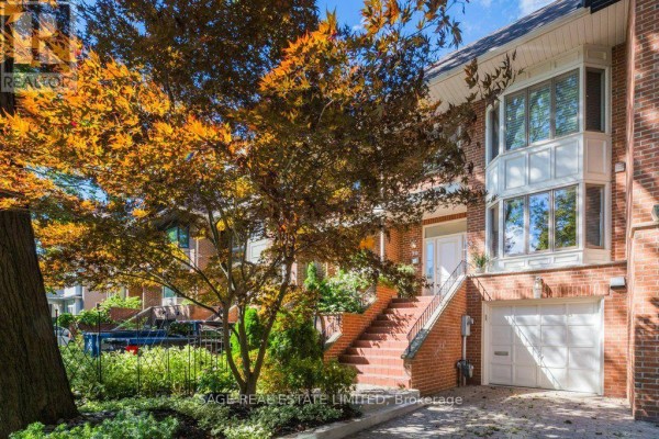 Brick townhouse exterior with entrance stairs, garage, and autumn foliage. - 70 Heath Street E, Toronto