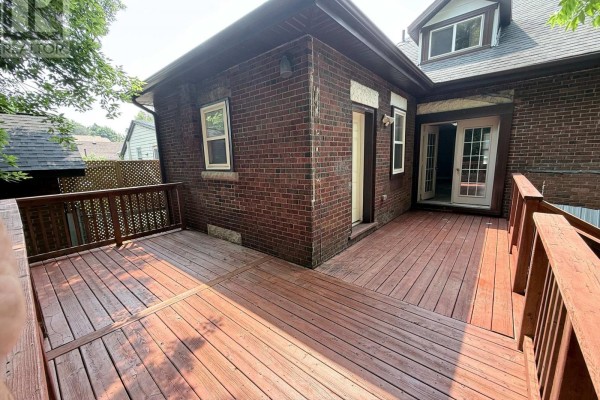 Expansive wooden deck with railings wraps around the back of the brick house. - 70 Huron Street, Guelph