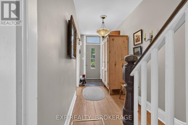 Interior view of a narrow hallway with light grey walls, wood floors, and a staircase. - 70 Livingston Avenue, Kingston