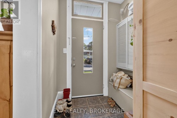 Front door interior view of a hallway with tiled floor, white trim, and storage bench. - 70 Livingston Avenue, Kingston