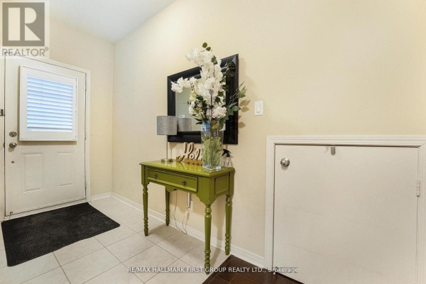 Entryway with green console table, decorative flowers, and coat closet - 70 Lovegrove Lane, Ajax