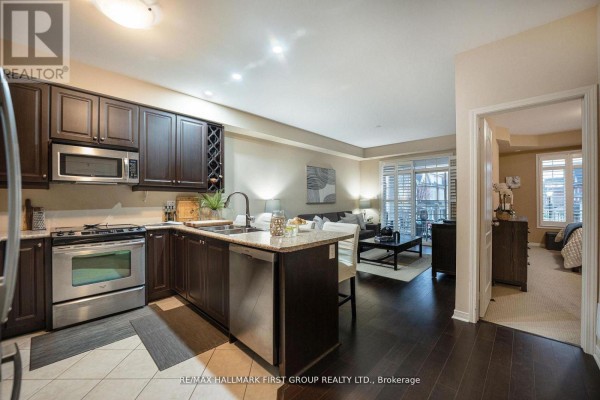 Open-concept kitchen with dark cabinetry, stainless steel appliances, and adjacent living area - 70 Lovegrove Lane, Ajax