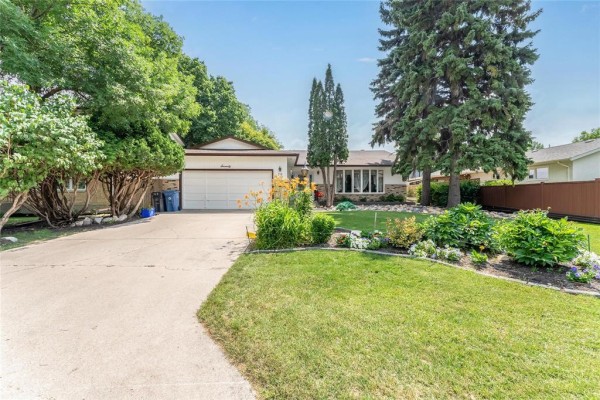 Driveway leading to the entrance of a house with lush green trees. - 70 Radcliffe Road, Winnipeg