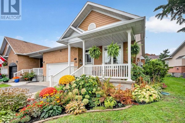 Front exterior of a townhouse with colorful flower beds and a covered porch. - 70 Sable Run Drive, Ottawa