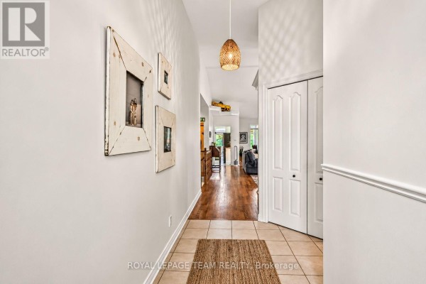 Interior hallway with tiled floor, framed art on the wall, and doors leading to rooms. - 70 Sable Run Drive, Ottawa