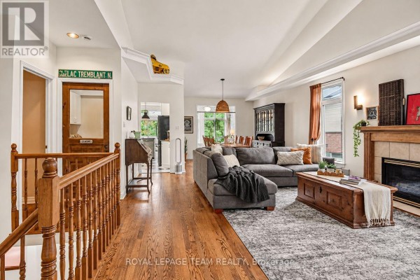 Open-concept living and dining area with a sectional sofa, fireplace, and hardwood floors. - 70 Sable Run Drive, Ottawa