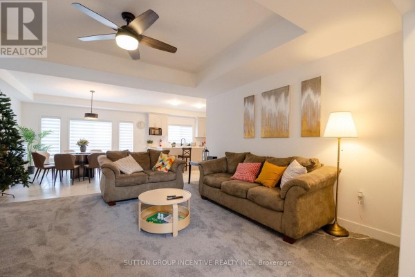 Living room with plush grey carpet, two brown sofas, a round coffee table, and an open view to the dining area and kitchen. - 70 Shipley Avenue, Collingwood