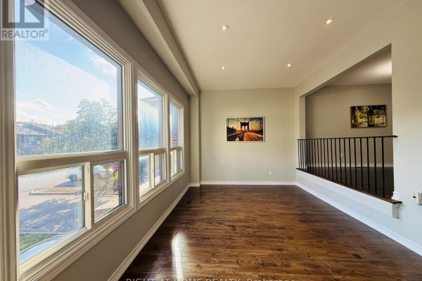 Spacious room with large windows, hardwood floors, and a railing overlooking another area. - 70 Spire Hillway Way, Toronto