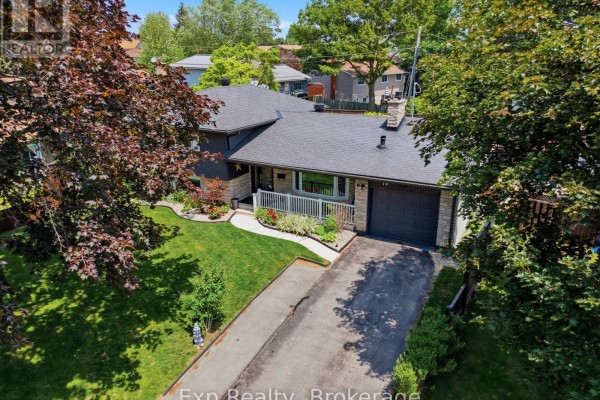 Exterior of a residential house with dark grey siding, stone facade, white porch railing, and a manicured lawn. - 70 Tripp Boulevard, Quinte West