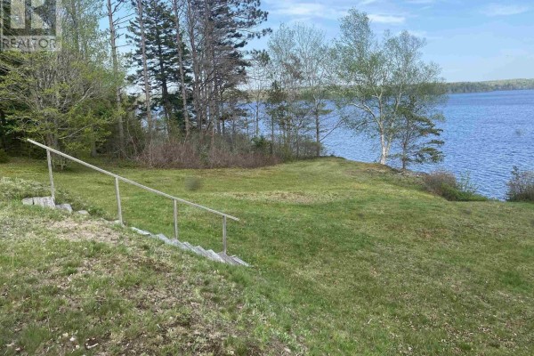 Water view of a calm blue lake surrounded by green trees under a cloudy sky. - 70 Whispering Pines Lane, North Range