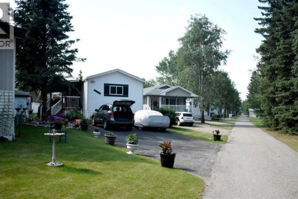Mobile homes with parked cars and outdoor decorations on a sunny day. - 700 Carmichael Lane, Hinton