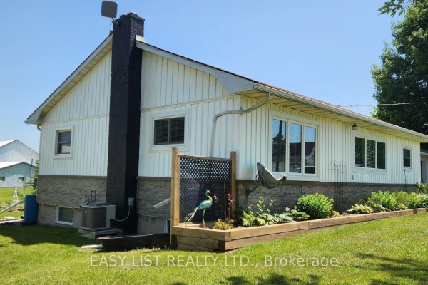 Rear exterior of a white house with a stone foundation and a raised garden bed. - 700 Norfolk County Road 28, Norfolk