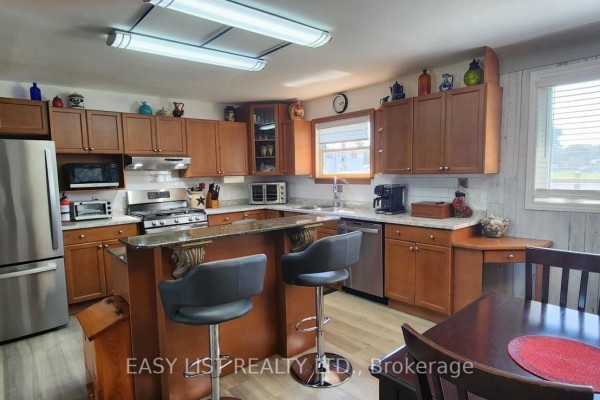 U-shaped kitchen with wood cabinets, granite countertops, and stainless steel appliances. - 700 Norfolk County Road 28, Norfolk