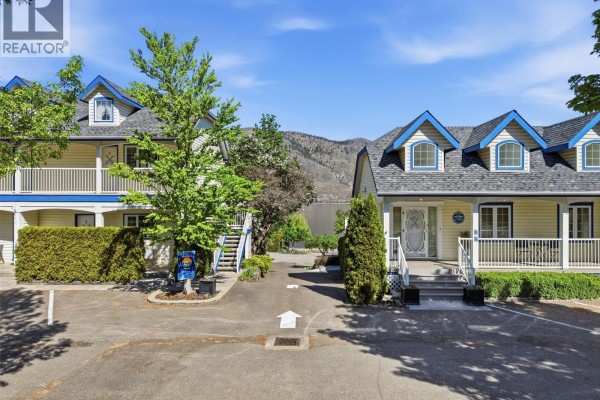 Two yellow buildings with blue trim, dormer windows, and porches, separated by a driveway. - 7001 Savona Access Road, Kamloops