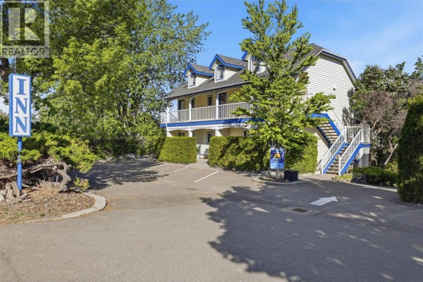 Side view of a yellow building with blue trim, an outdoor staircase, and a prominent 'Inn' sign. - 7001 Savona Access Road, Kamloops