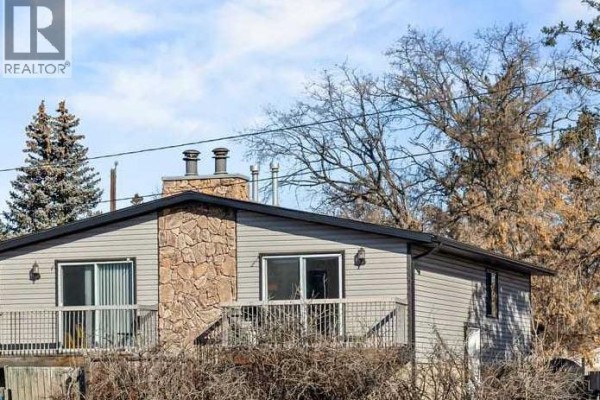 Side view of duplex featuring stone facade and balcony - 7006a Bowness Road Nw, Calgary