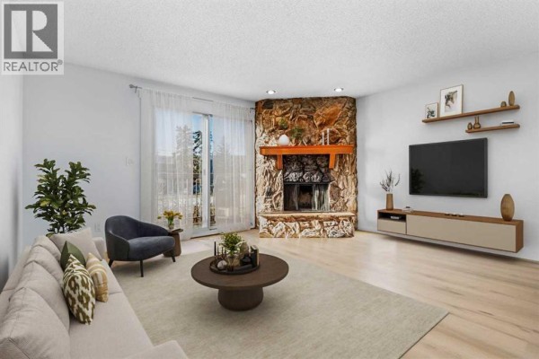 Empty living room with stone fireplace and sliding glass door to balcony - 7006a Bowness Road Nw, Calgary