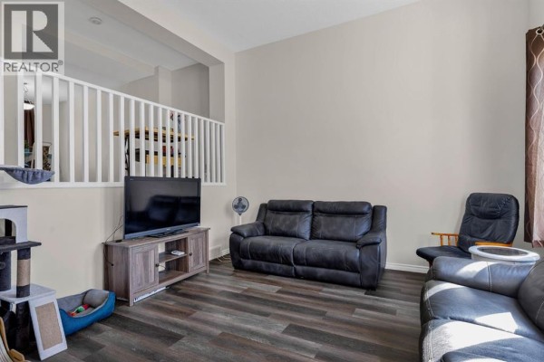 Living room with dark leather sofas, media console with television, and cat tree. - 7008, 2370 Bayside Road Sw, Airdrie