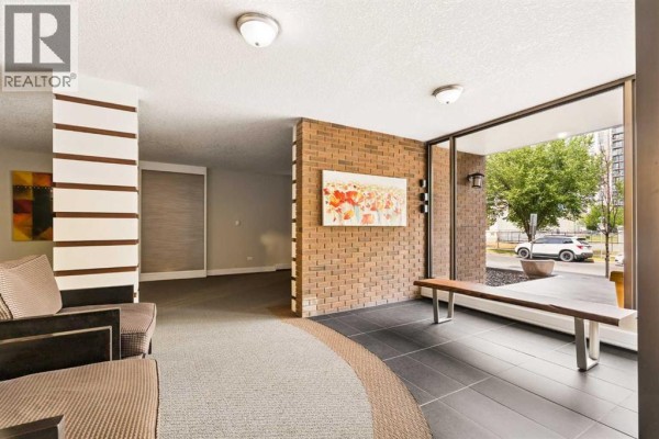 Building lobby with brown brick accent walls, a wooden bench, and large windows. - 701, 1123 13 Avenue Sw, Calgary