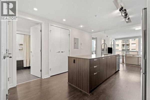 Interior view of an apartment showing a kitchen island, hallway, and bathroom. - 701, 626 14 Avenue Sw, Calgary