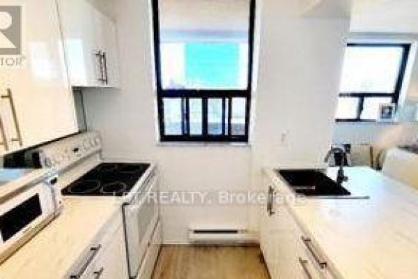 White kitchen with stainless steel appliances, white cabinets, and a black sink and faucet. - 701 - 105 Mccaul Street, Toronto