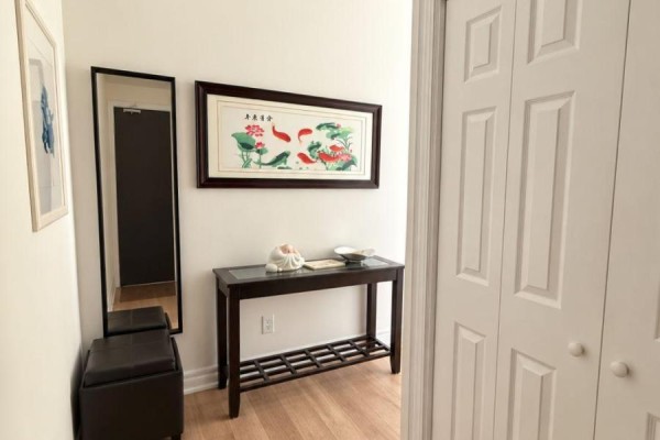 Apartment entryway with wood floors, a console table, and mirrored cabinet. - 701 - 17 Ruddington Drive, Toronto