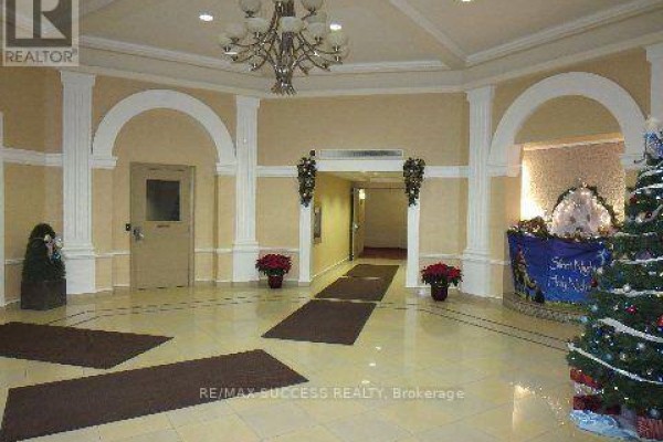 Lobby area with tiled floors, arched doorways, columns, a chandelier, and festive Christmas decorations. - 701 - 220 Forum Drive, Mississauga
