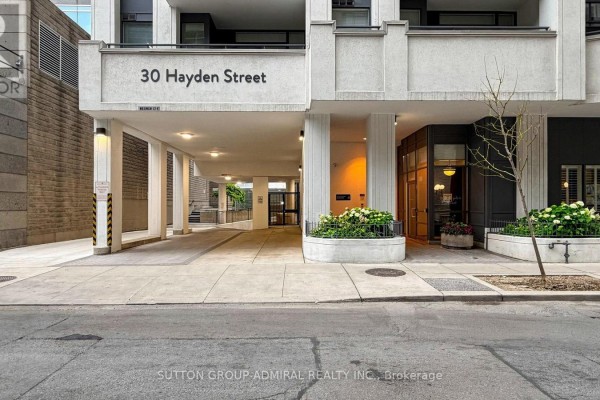 Entrance and driveway of a condo building with covered walkway and glass doors. - 701 - 30 Hayden Street, Toronto