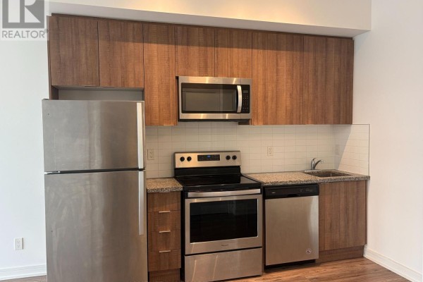 Close-up of a condo kitchen with stainless steel appliances, wood cabinets, and granite counters. - 701 - 621 Sheppard Avenue E, Toronto