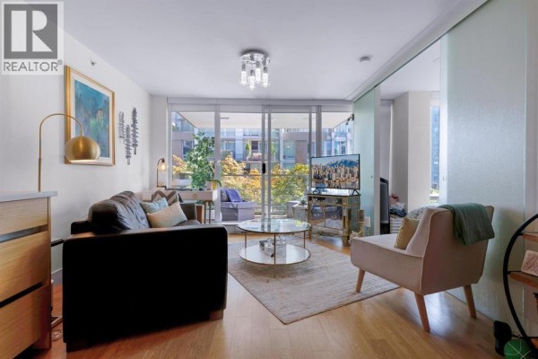 Living room with a dark sofa, armchair, and coffee table on a woven rug. - 701 565 Smithe Street, Vancouver