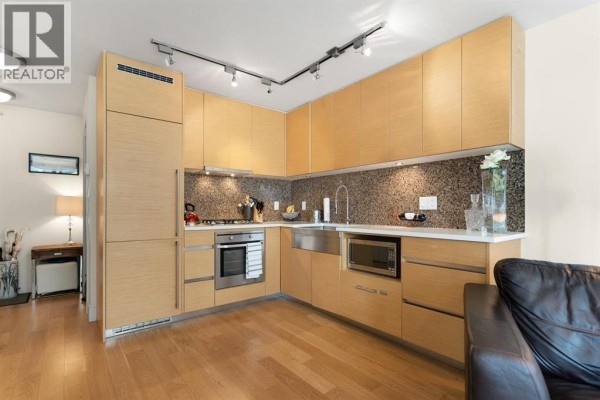 L-shaped kitchen with light wood cabinets, stainless steel appliances, and a granite backsplash. - 701 565 Smithe Street, Vancouver